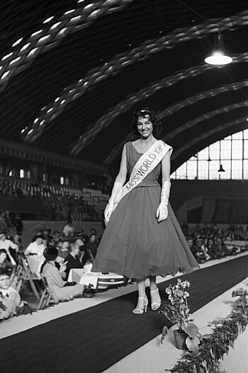 Schwarzweißfoto: Eine Frau mit dem Banner "Miss World 1956" geht über einen Laufsteg in der Halle Münsterland.
