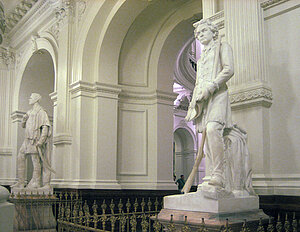 Zwei Statuen an den Säulen von Bögen, die den Durchgang in einen weiteren Raum erlauben. Im Vordergrund eine Statue von Sam Houston im Hintergrund Statue von Stephen F. Austin.