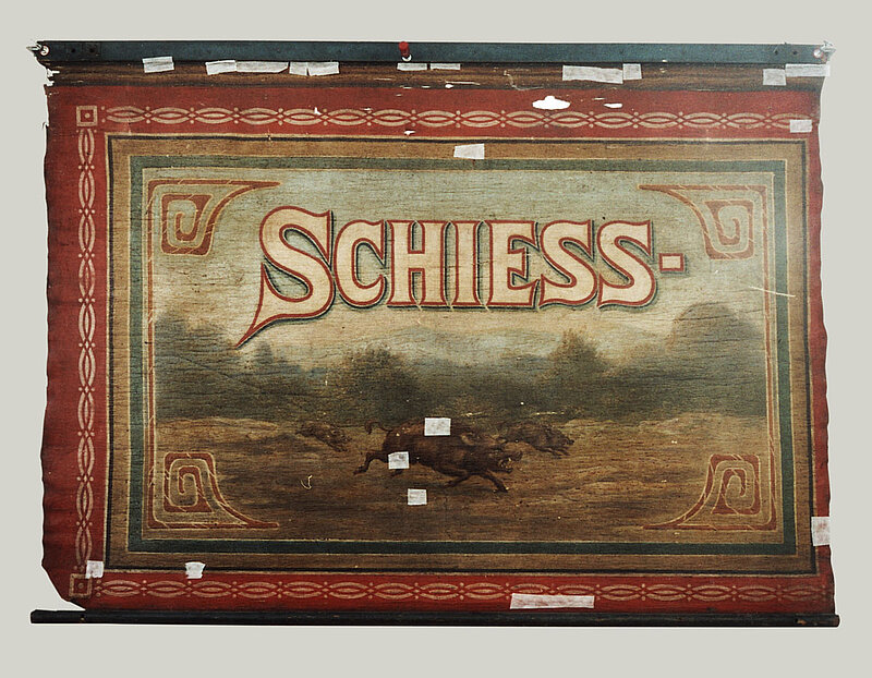Teil eines Rollbildes der Schießhalle Schönhagen-Genert: Ein Gemälde von Wildschweinen rennen unter dem Beginn eines Schriftzuges. Nur das Wort "Schiess-" ist zu lesen.